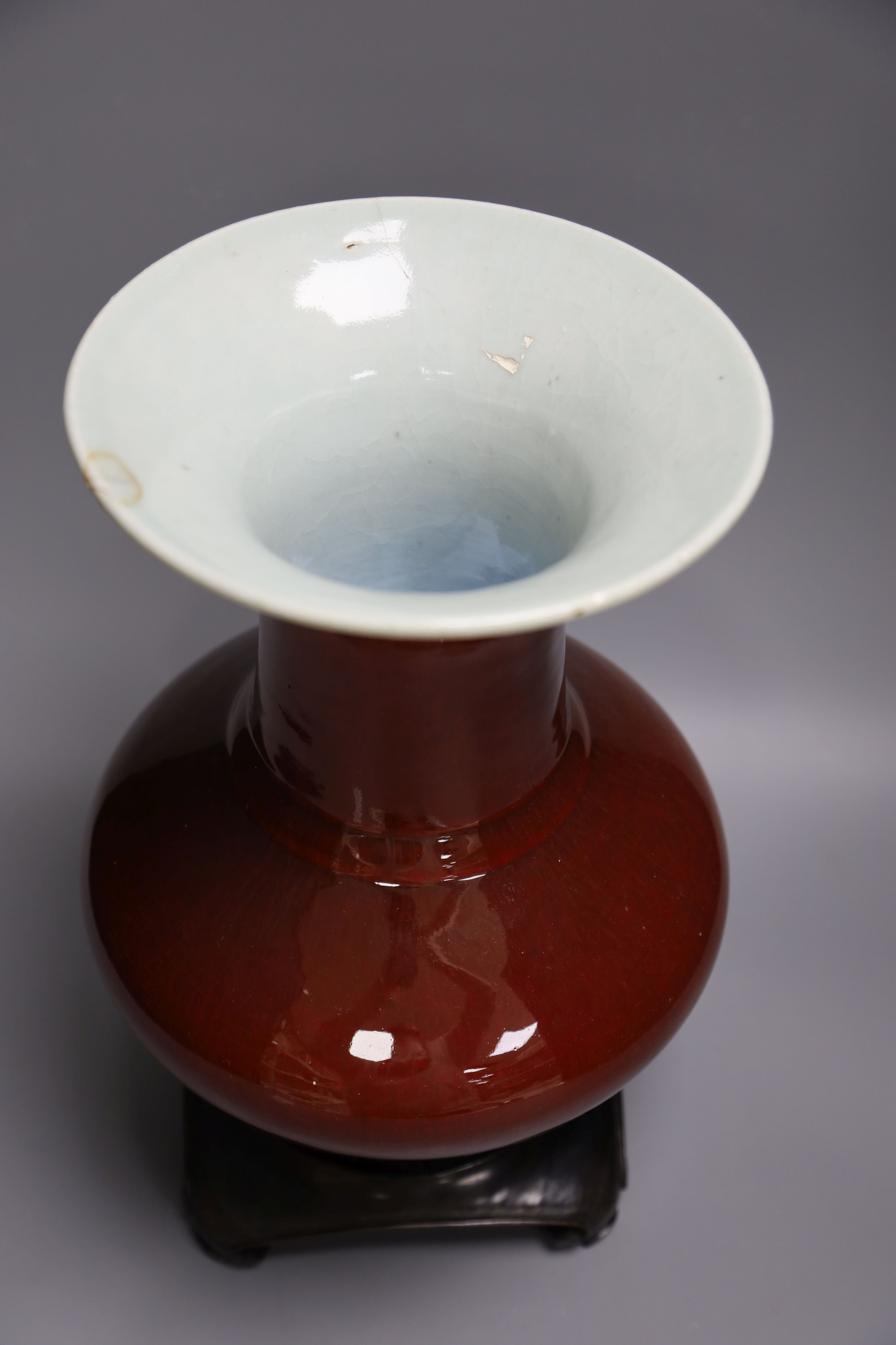 A 19th century Chinese sang de boeuf vase of squat baluster form with everted rim (a.f.), on square hardwood stand, overall height 35.5